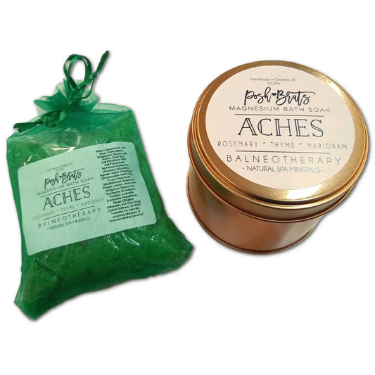 A green pouch and matching tin of Posh Brats Aches Aromatherapy Bath Salt, infused with essential oils, eucalyptus, rosemary, thyme, and marjoram, offer a soothing bath experience. The tin has a metal lid; the pouch is slightly transparent.