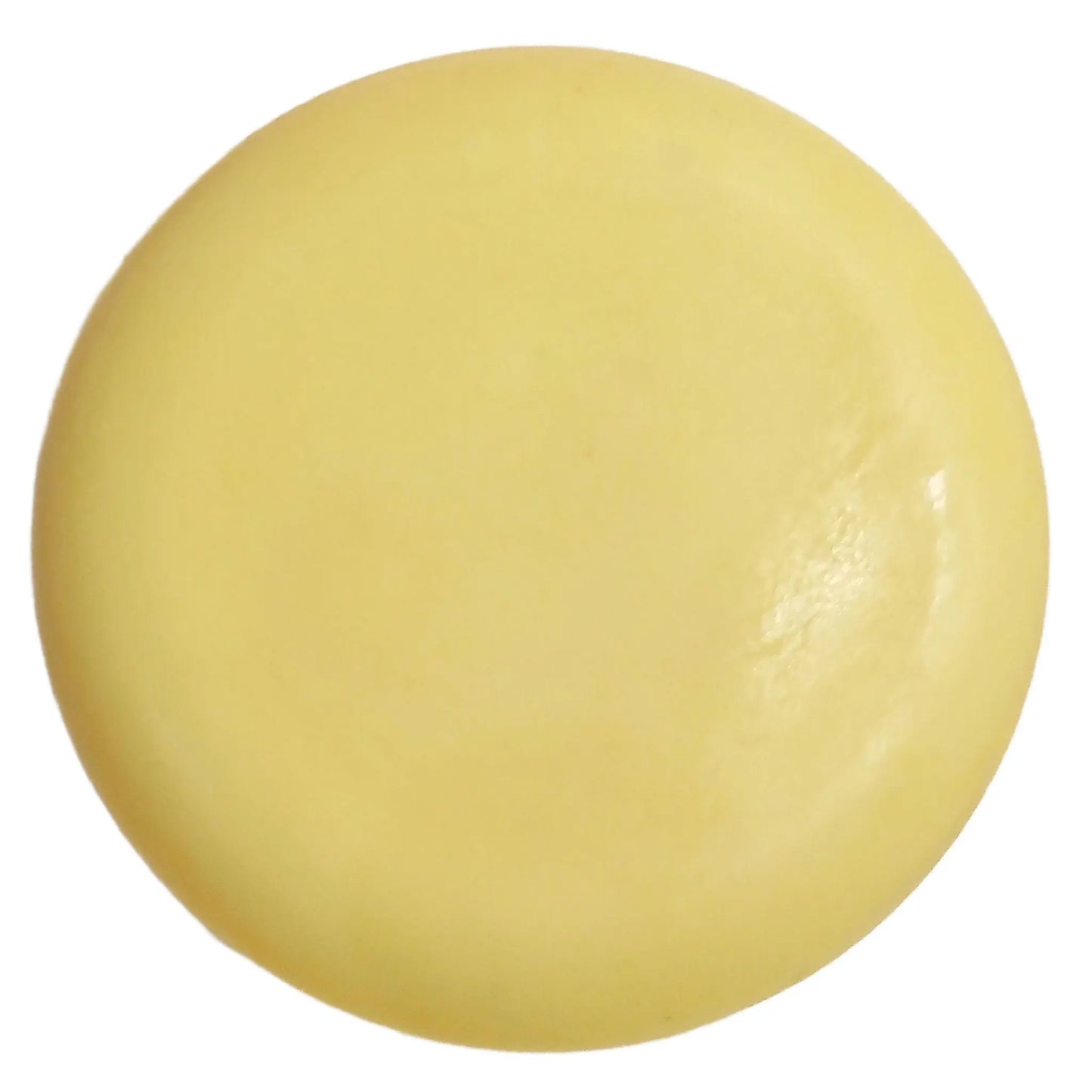 A close-up of the Amalfi Lemon + Sea Salt Cleansing Bar by Posh Brats, with a round, smooth, pale yellow design resembling a disc. Its glossy texture and subtle color variations are set against a plain white background.