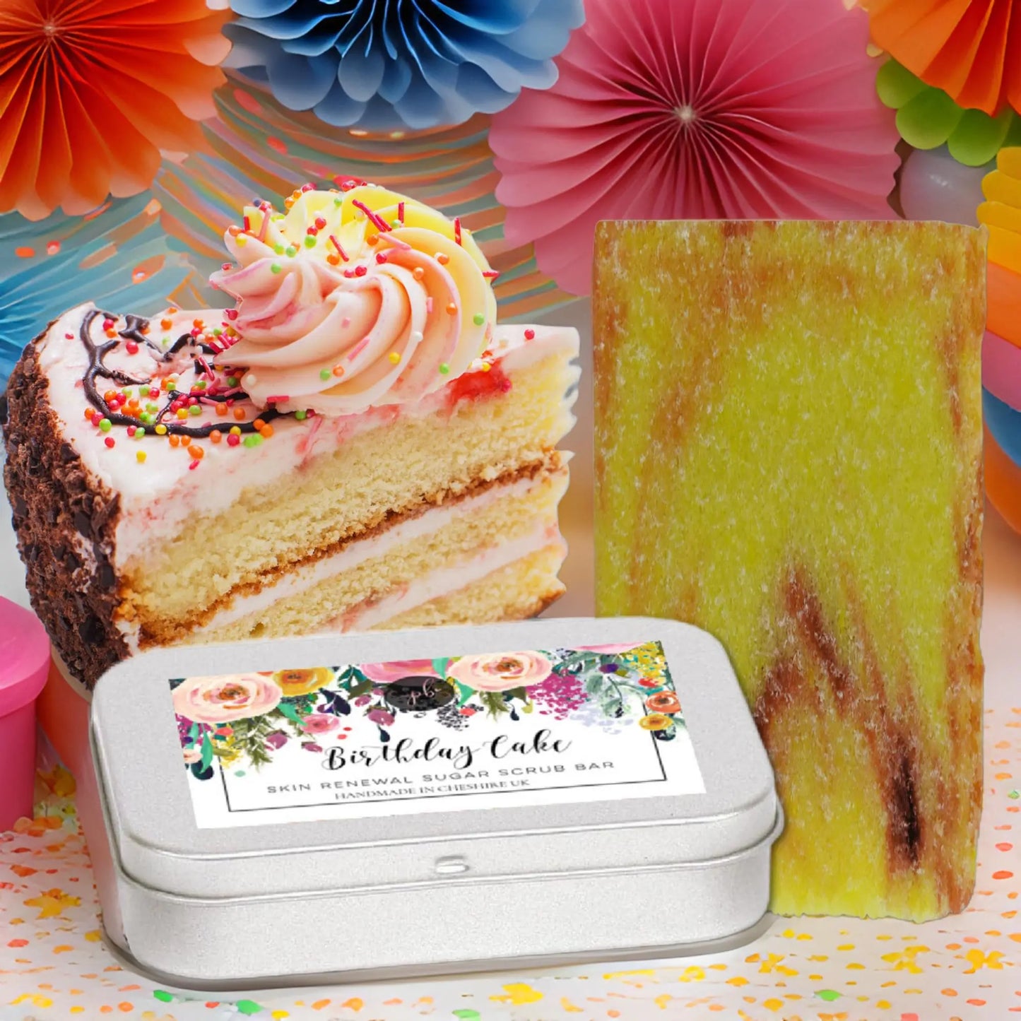 A festive setup showcases cake with sprinkles and paper decor. In front, a green soap bar and a tin labeled Posh Brats Birthday Cake Sugar Scrub Bar are ideal for vegan shower scrub fans.
