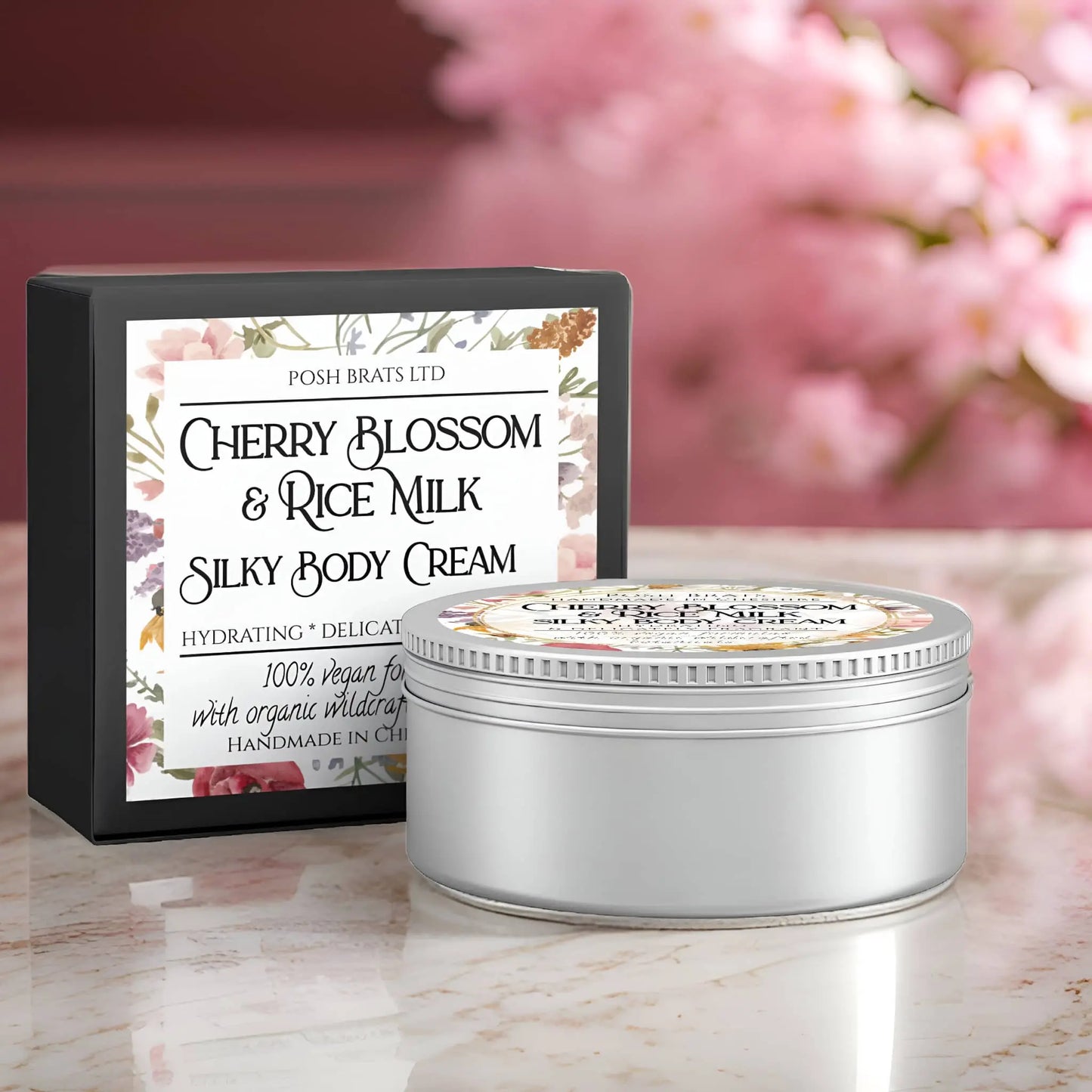 A jar of Posh Brats Cherry Blossom + Rice Milk Silky Body Butter Cream rests by its floral-themed box. The Hydrating & Delicate label is enhanced by soft pink blossoms in the background, bringing elegance to the scene.
