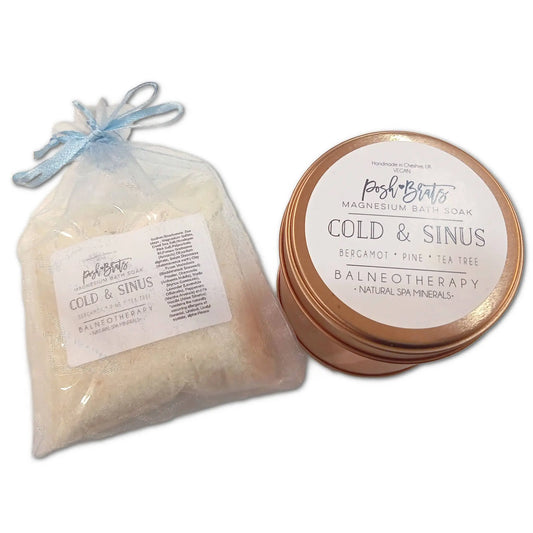 A tin of Posh Brats Cold Sinus Magnesium Bath Salt features eucalyptus peppermint oils and bergamot, accompanied by a sheer bag. The packaging highlights balneotherapy and natural spa minerals for a refreshing experience.