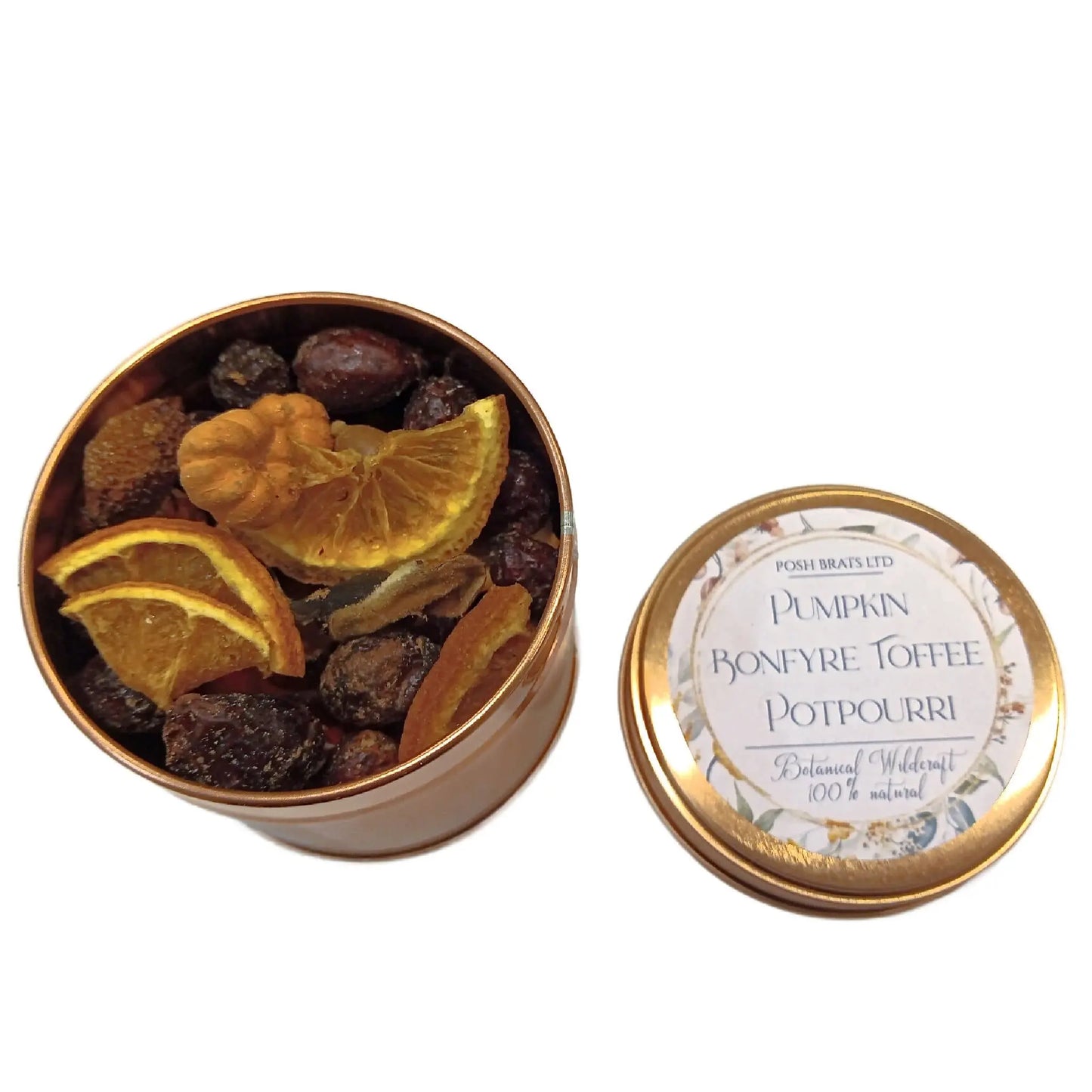 Open a tin of vibrant potpourri with dried orange slices, herbs, and small berries. The lid beside it reads Pumpkin Bonfyre Toffee, denoting a fragrant mix from Posh Brats Wildcraft Botanical Potpourri collection.