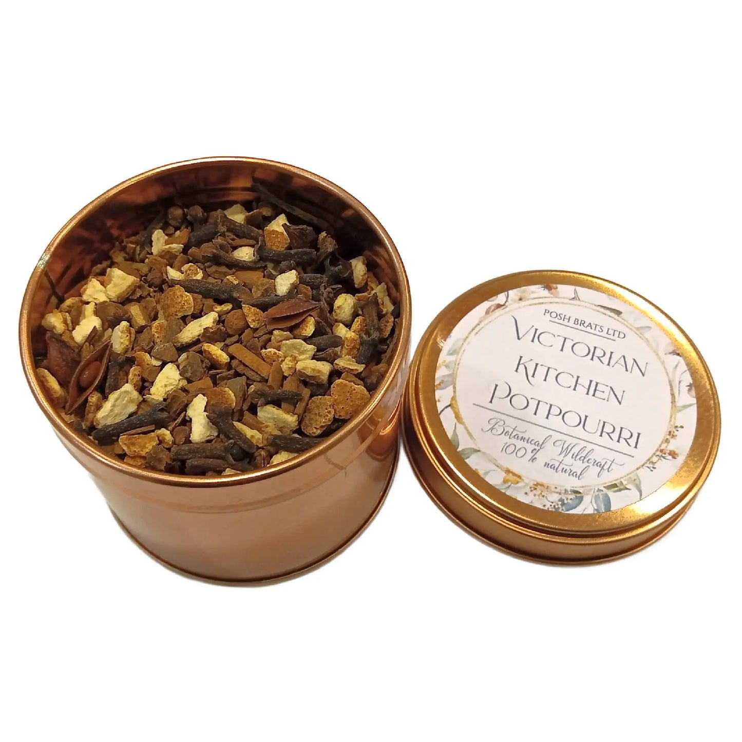 An open copper tin of Wildcraft Botanical Potpourri by Posh Brats reveals a fragrant blend of dried flowers and botanicals. The round lid beside the tin displays the same label with a floral border.