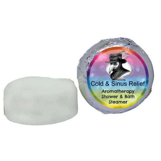 A small white Cold Sinus Aromatherapy Shower Steamer by Posh Brats is placed next to its foil wrap. The label features a rainbow and a plague doctor, promising congestion relief with each use.