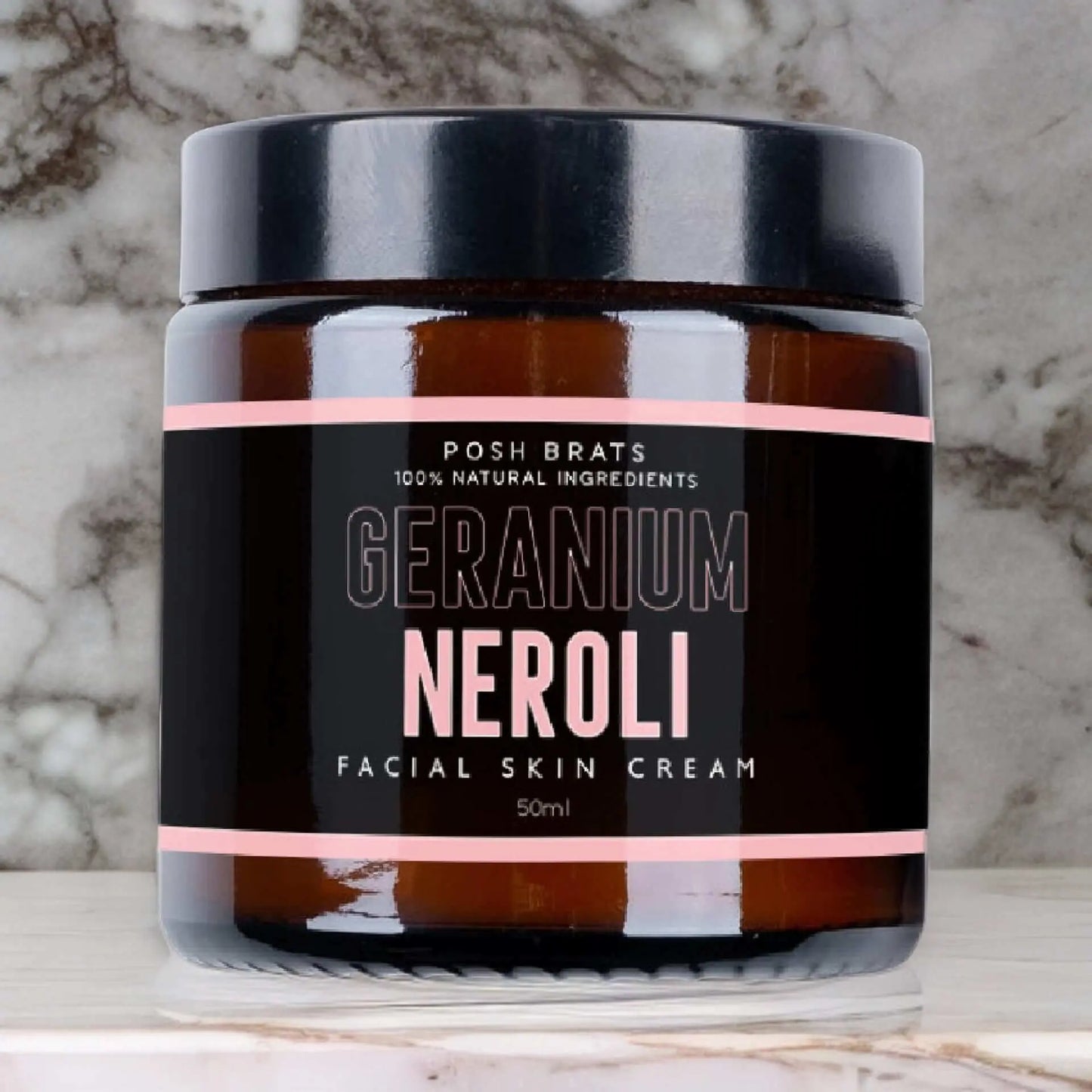 A brown jar labeled Geranium Neroli Skin Cream by Posh Brats, featuring skin-balancing botanical extracts and 100% Natural Ingredients, has a black lid and is elegantly set on a marble surface.