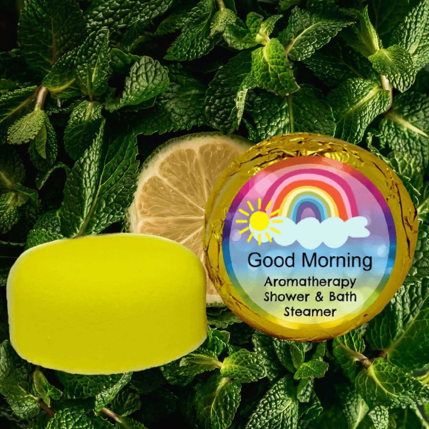A Posh Brats Good Morning Aromatherapy shower steamer with a bright sun and rainbow design sits on mint leaves and a lemon slice. Infused with essential oils, it offers a refreshing morning boost.