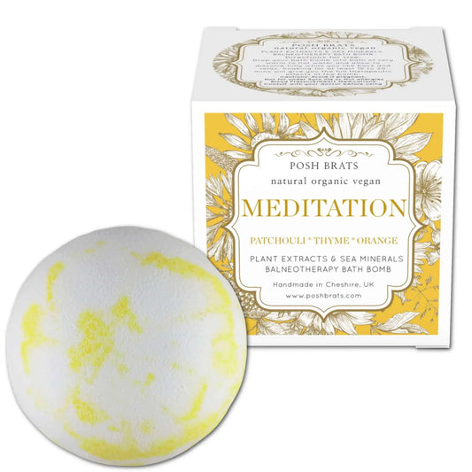A yellow-patched round Meditation Aromatherapy Bath Bomb by Posh Brats is displayed next to a white Posh Brats Meditation box. It offers a relaxing experience with patchouli, thyme, and orange essential oils. Made in Cheshire, UK, its natural, organic, and vegan.