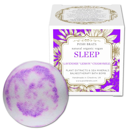 A round purple and white marbled Sleep Aromatherapy Bath Bomb by Posh Brats sits beside its botanically themed box, showcasing relaxing essential oils like lavender, lemon, and chamomile. This product emphasizes its natural, organic, and vegan qualities.