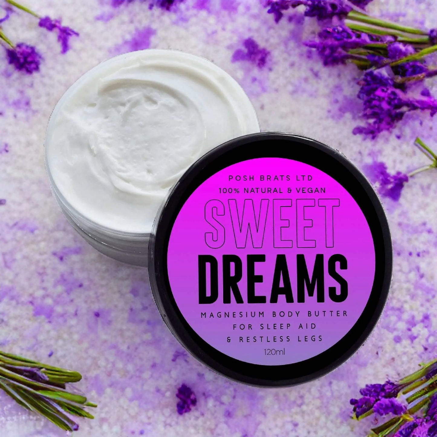 An open container of Sweet Dreams Magnesium Body Butter by Posh Brats sits beside a jar of white cream. Purple dried flowers and bath salts surround it, emphasizing its role as a relaxation and deep sleep aid for restless legs.