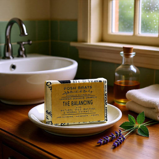 Bar of soap on a plate with a bottle and towel in the background, likely in a bathroom setting.