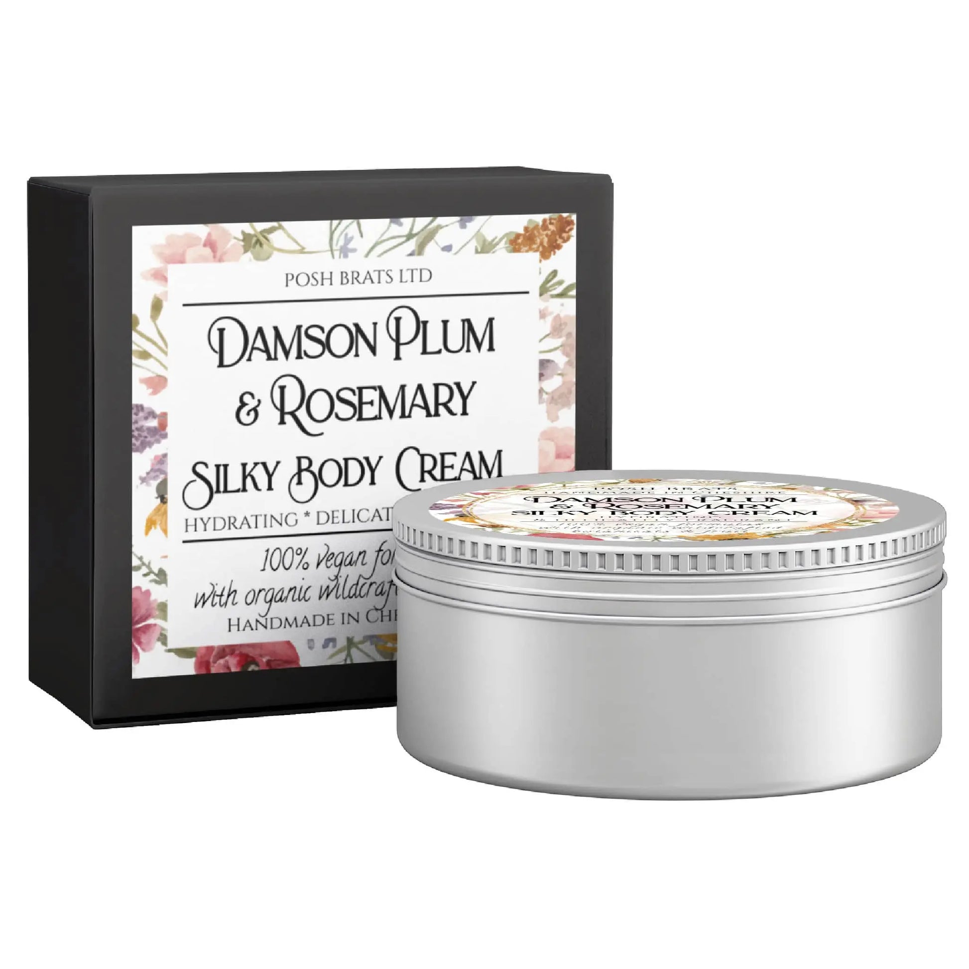 A round silver tin of Posh Brats Damson Plum + Rosemary Silky Body Butter Cream, featuring a floral label and highlighting its hydrating and vegan properties, stands next to its matching decorative box.