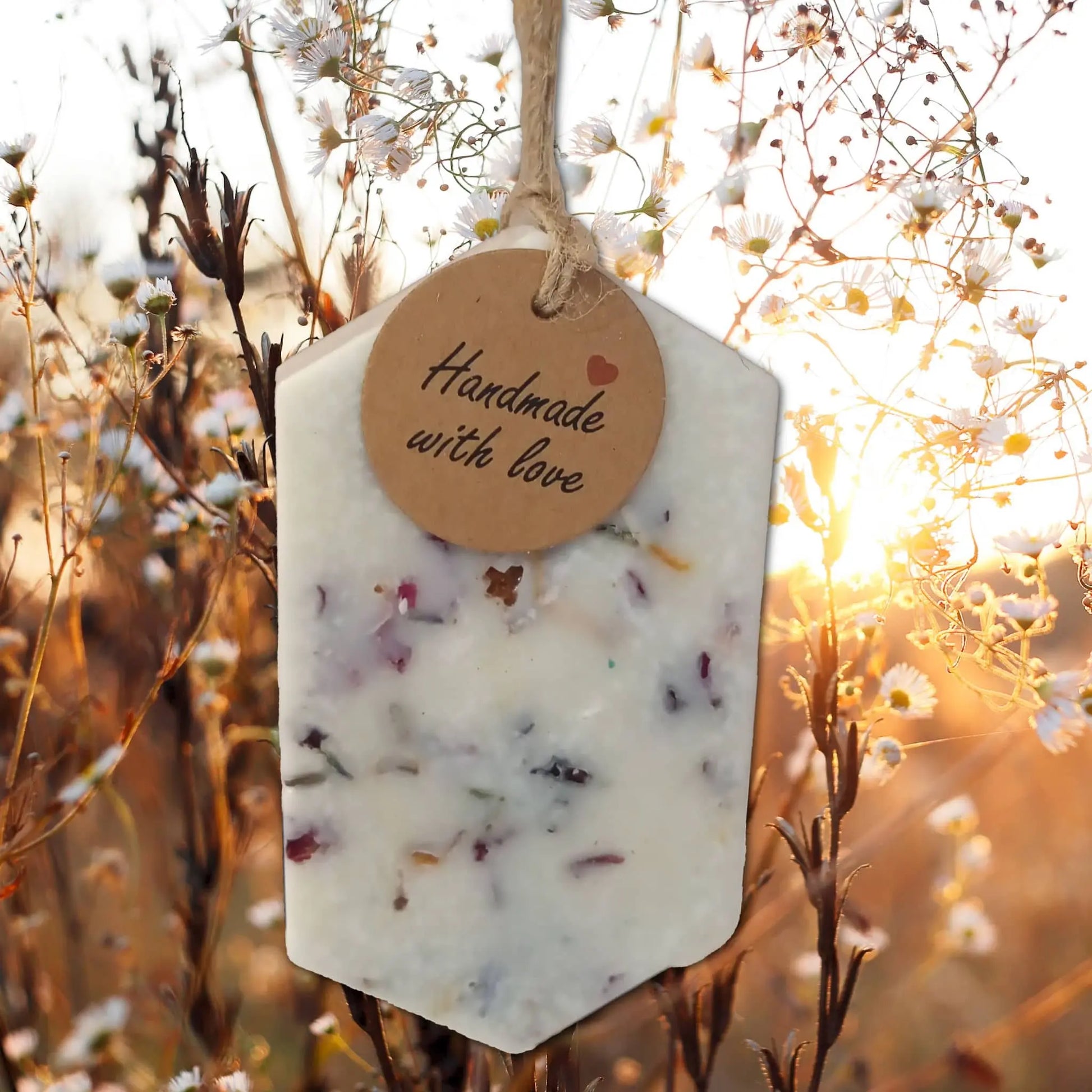 The Posh Brats Wax Potpourri Sachet Tag, crafted from sustainable coconut and soy wax, features handpicked botanicals. A round tag reading Handmade with love complements the charming scene of delicate wildflowers lit by a sunset glow.