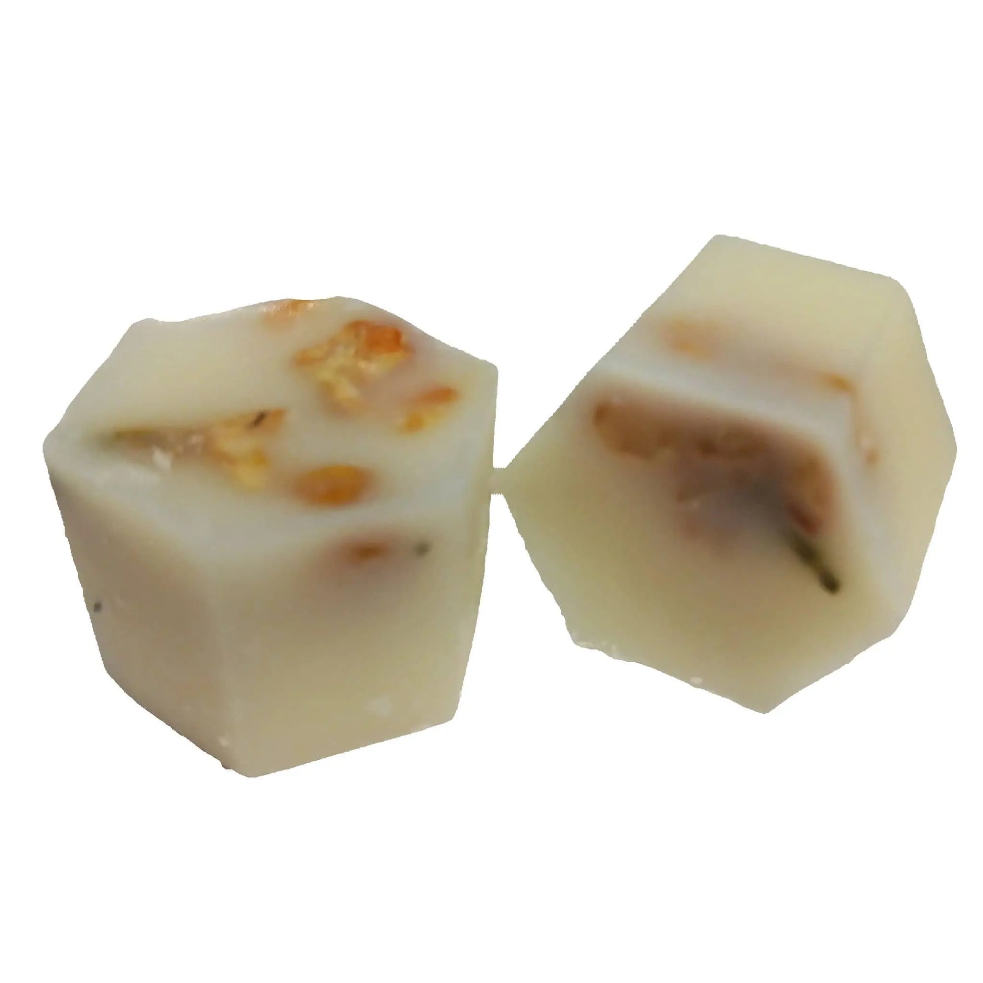 Inside the Posh Brats Woodbine Jessamy Botanical Butter Bath Melt, two hexagonal pieces of white chocolate with caramel and nut chunks are embedded. The smooth surface complements the textured interior, crafted with cocoa butter—one piece whole and one sliced to show its filling.