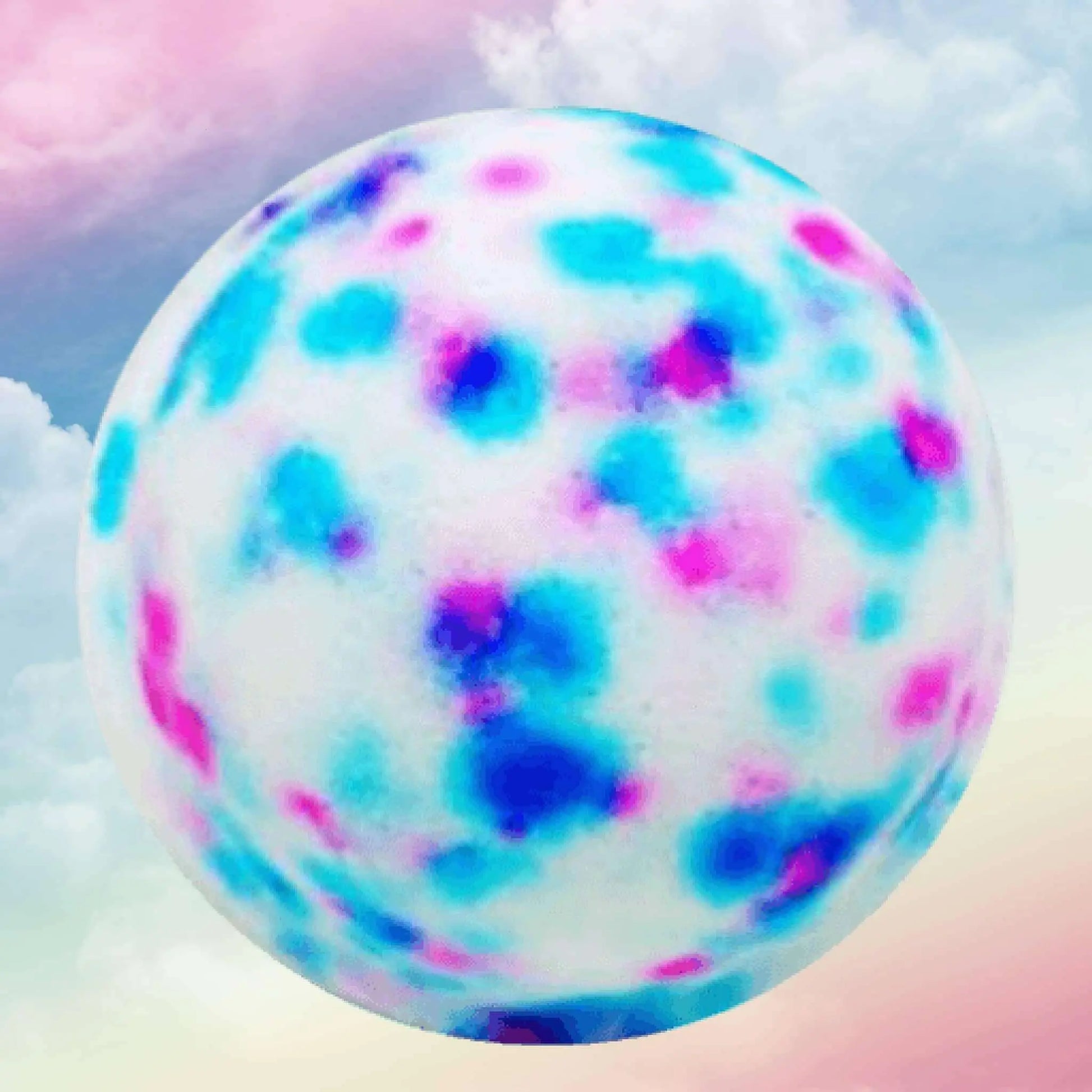 The sphere mirrors a calming foamy haven with a white surface speckled in uneven blue and pink, like Posh Brats Baby Powder Fizzy Bath Bomb. It rests against a soft, pastel sky with gentle clouds.