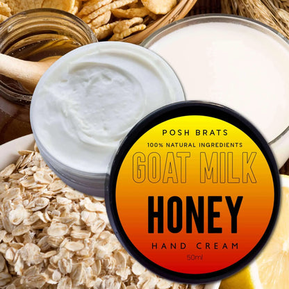 A jar of Posh Brats Goat Milk Aloe Vera Honey Soothing Hand Cream is artfully displayed among oats, honey with a dipper, wheat stalks, and creamy lotion. The blend of 100% natural ingredients, including Aloe Vera, is beautifully highlighted on the label.