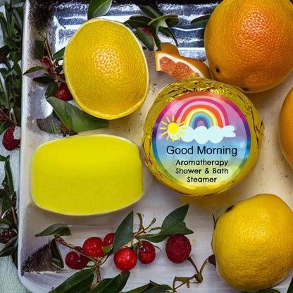 The Good Morning Aromatherapy Shower Steamer by Posh Brats, infused with essential oils, rests on a sleek tray amidst citrus and red berries for a vibrant and refreshing start to your day.