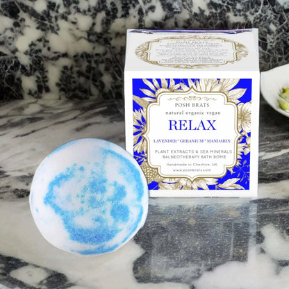 A round blue and white Relax Aromatherapy Bath Bomb in front of a square Relax box is infused with lavender, geranium, and mandarin oils for stress relief. Its vegan, organic, natural, and made by Posh Brats in Cheshire, UK.